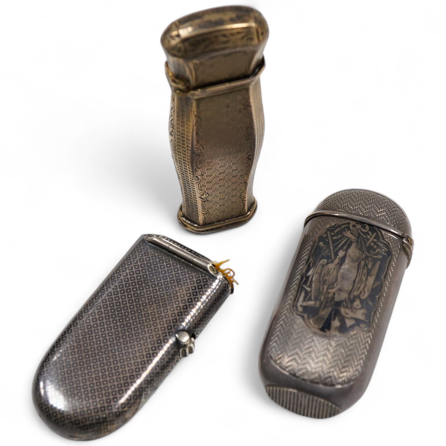 A 19th century continental engine turned parcel gilt white metal vesta case, 66mm, (lion head mark), together with two late 19th century continental white metal and niello vesta cases, one decorated with game.